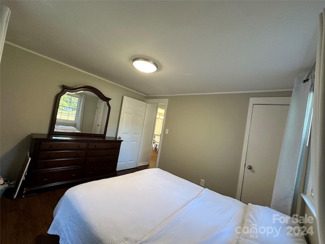 bedroom with lofted ceiling, crown molding, and dark wood-type flooring