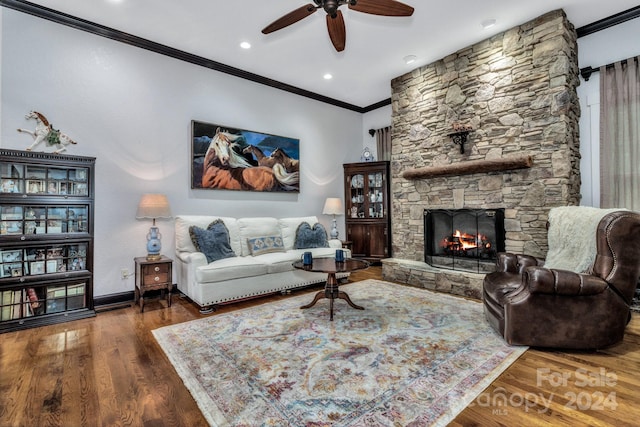 living room featuring dark wood-type flooring, ornamental molding, a fireplace, and ceiling fan