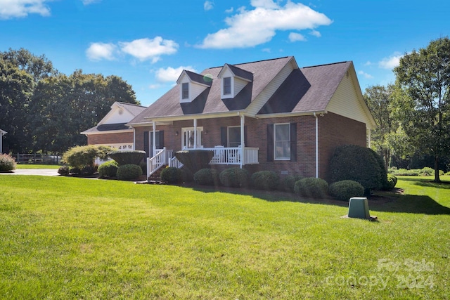 cape cod home featuring a front lawn and covered porch