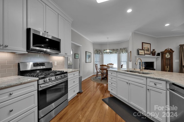 kitchen with sink, ornamental molding, white cabinetry, light hardwood / wood-style flooring, and appliances with stainless steel finishes