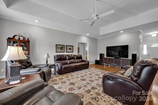 living room featuring light hardwood / wood-style floors, a tray ceiling, crown molding, and ceiling fan