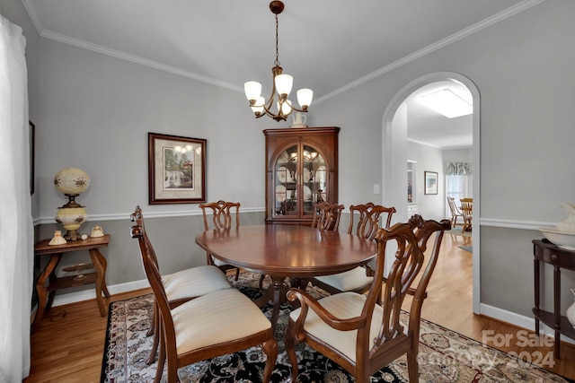 dining room featuring ornamental molding, light wood-type flooring, and an inviting chandelier