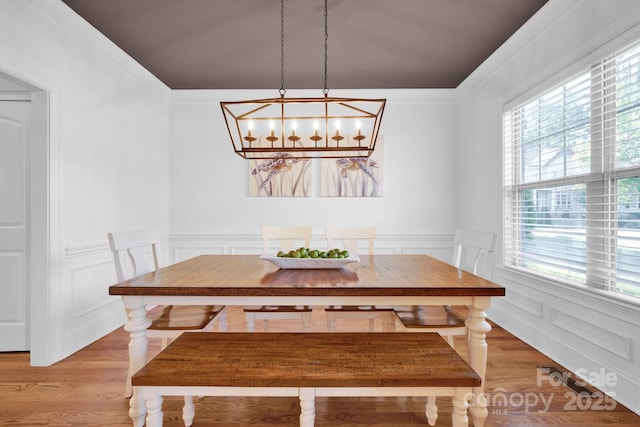 dining room featuring hardwood / wood-style floors, ornamental molding, and a chandelier