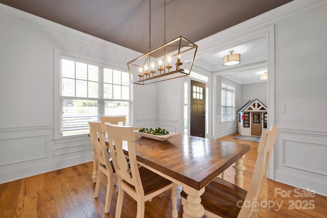 dining space with ornamental molding and light wood-type flooring