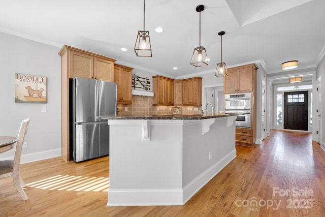 kitchen with dark stone countertops, backsplash, a kitchen bar, stainless steel appliances, and a center island with sink