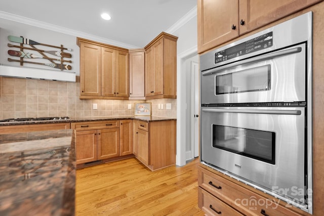 kitchen with crown molding, light hardwood / wood-style flooring, backsplash, stainless steel appliances, and dark stone counters