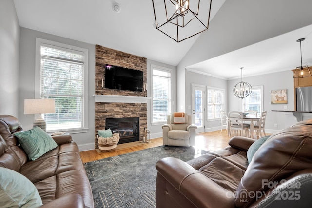 living room featuring an inviting chandelier, a stone fireplace, vaulted ceiling, and hardwood / wood-style flooring