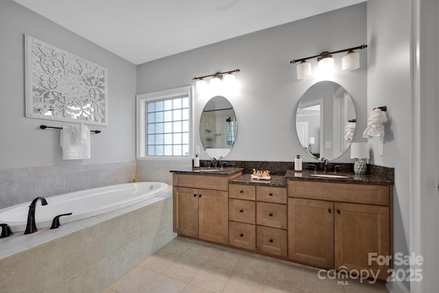 bathroom featuring tile patterned flooring, vanity, and tiled bath