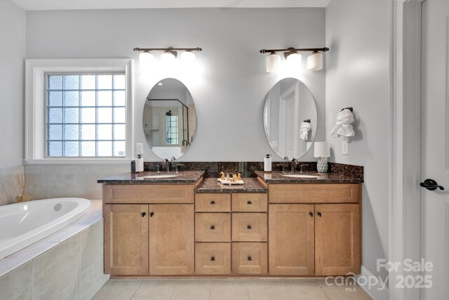 bathroom with tile patterned floors, vanity, and tiled tub