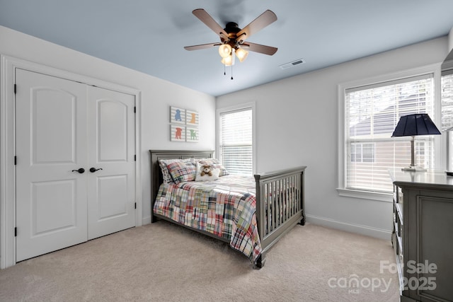 bedroom with ceiling fan, a closet, and light carpet