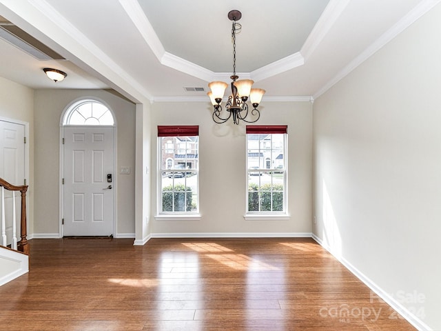 entrance foyer featuring an inviting chandelier, ornamental molding, hardwood / wood-style flooring, and a raised ceiling