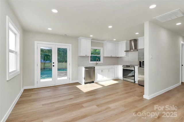 kitchen featuring french doors, sink, wall chimney range hood, stainless steel appliances, and white cabinets