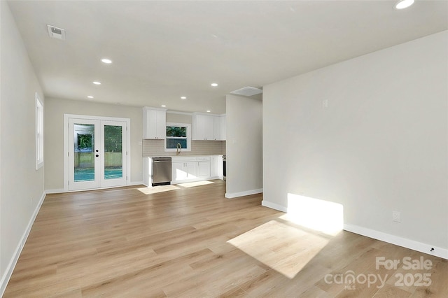 unfurnished living room featuring french doors, sink, and light hardwood / wood-style floors