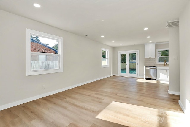 unfurnished living room featuring french doors, sink, and light hardwood / wood-style flooring