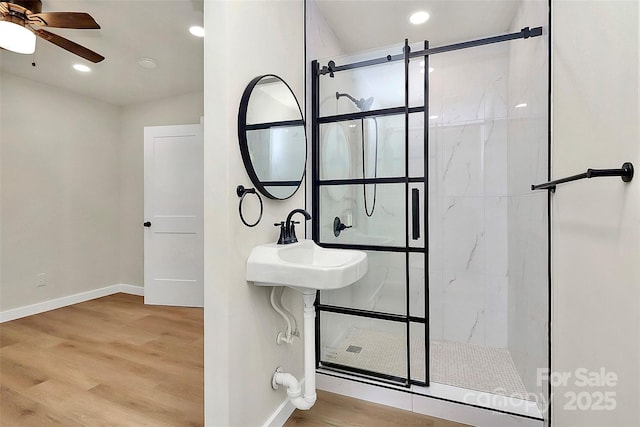 bathroom with wood-type flooring, tiled shower, sink, and ceiling fan