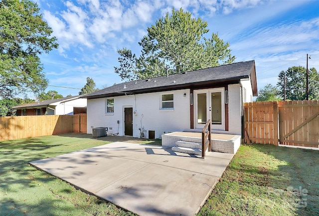 rear view of house with cooling unit, a patio, and a lawn