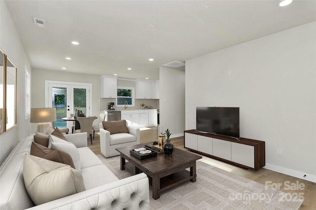 living room featuring sink, light hardwood / wood-style flooring, and french doors