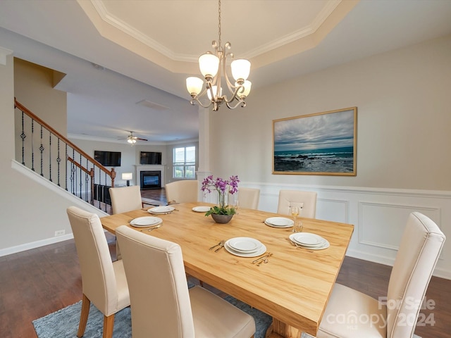 dining room featuring ornamental molding, a tray ceiling, ceiling fan with notable chandelier, and dark hardwood / wood-style flooring