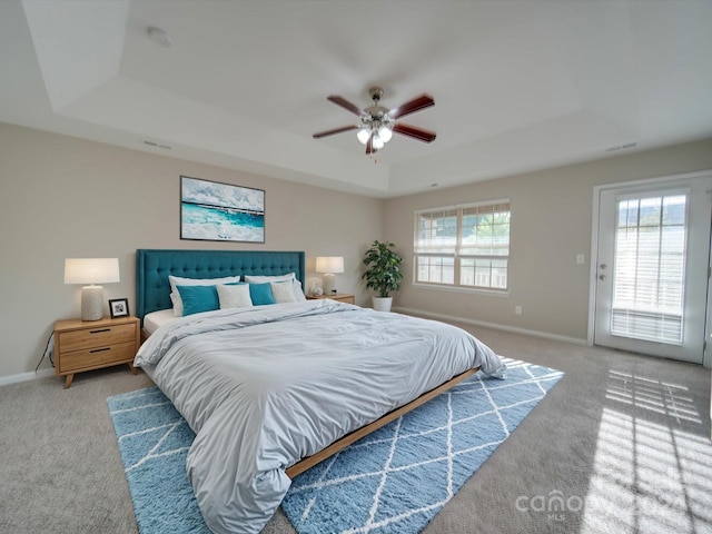 bedroom featuring ceiling fan, a tray ceiling, and carpet floors