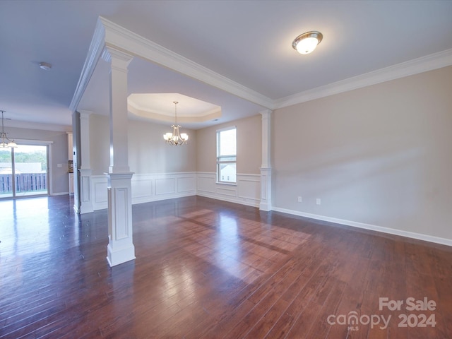 empty room with ornate columns, ornamental molding, dark hardwood / wood-style flooring, and a chandelier