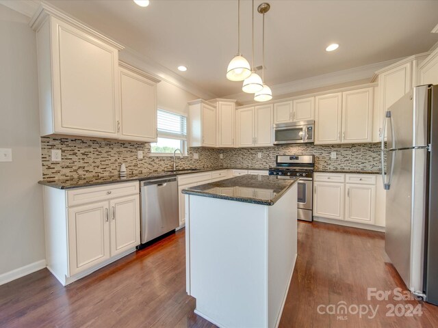 kitchen with a center island, appliances with stainless steel finishes, pendant lighting, and dark hardwood / wood-style floors