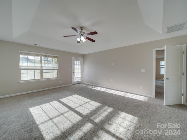 unfurnished room featuring light carpet, a raised ceiling, and ceiling fan