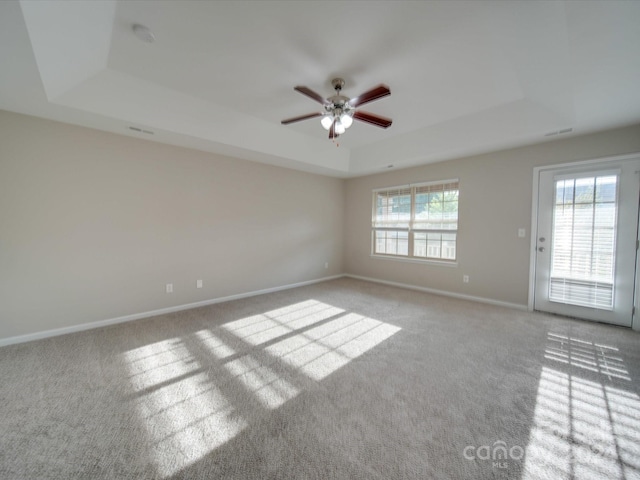 carpeted empty room with a tray ceiling and ceiling fan