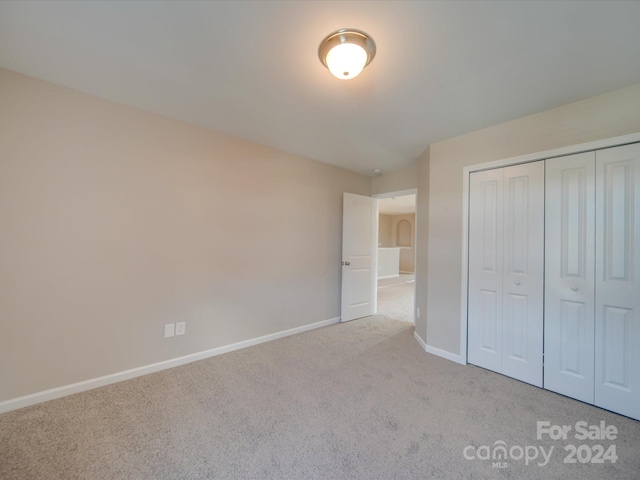 unfurnished bedroom with a closet and light colored carpet