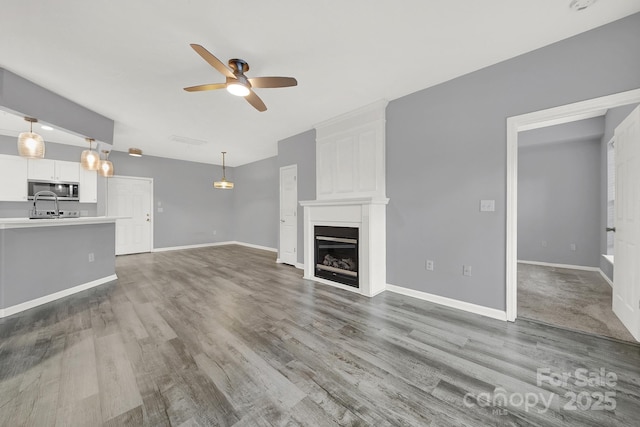 unfurnished living room featuring hardwood / wood-style flooring, ceiling fan, and a fireplace