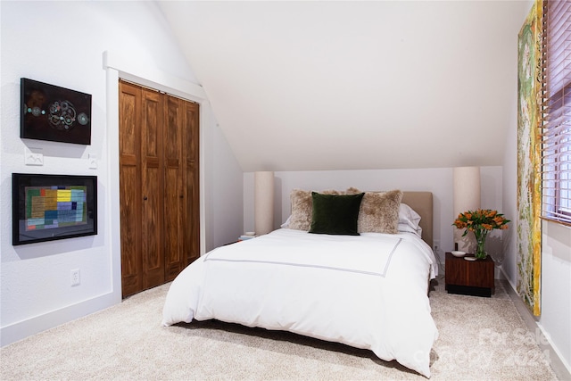 carpeted bedroom with a closet and vaulted ceiling