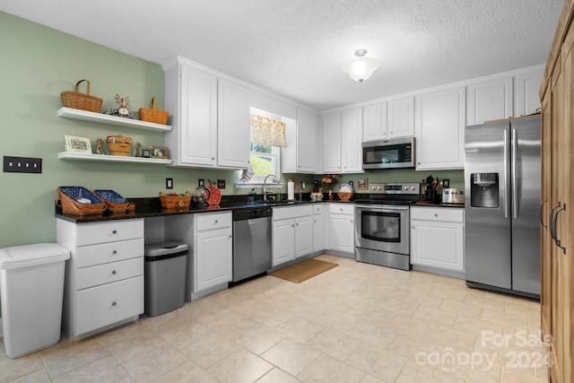 kitchen featuring a textured ceiling, sink, stainless steel appliances, and white cabinets