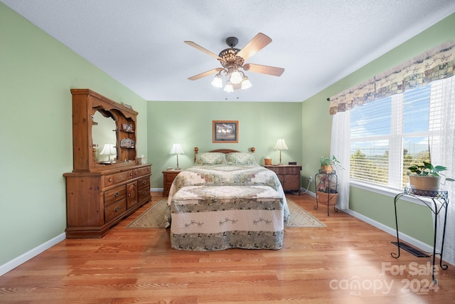 bedroom featuring light wood-type flooring, ceiling fan, and a textured ceiling