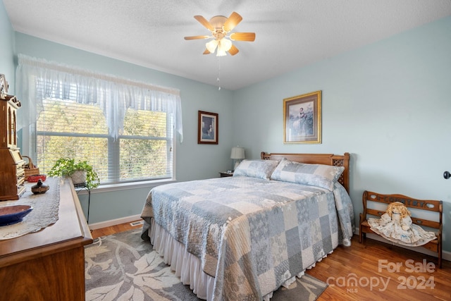 bedroom with ceiling fan, a textured ceiling, and light hardwood / wood-style flooring