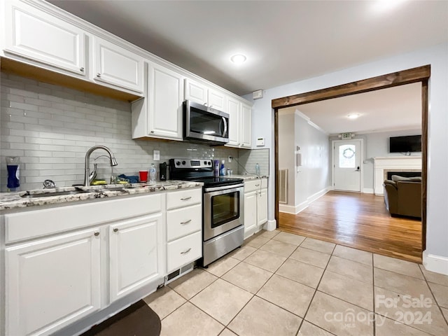 kitchen featuring sink, light hardwood / wood-style flooring, white cabinetry, appliances with stainless steel finishes, and decorative backsplash