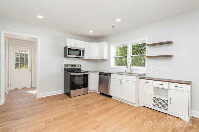 kitchen featuring appliances with stainless steel finishes, a wealth of natural light, white cabinetry, and sink