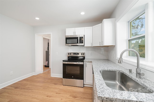 kitchen featuring light wood-type flooring, tasteful backsplash, white cabinets, sink, and appliances with stainless steel finishes