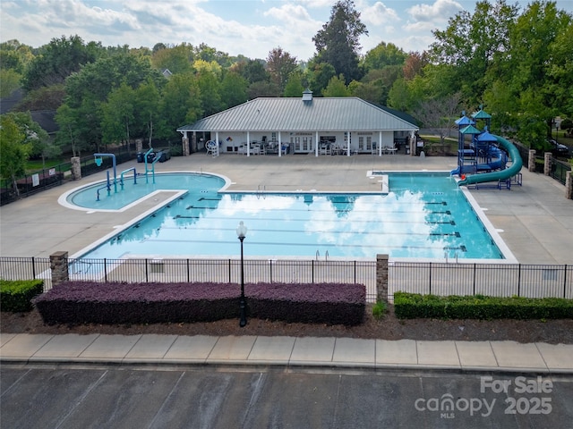 view of swimming pool featuring a patio area, a playground, and a water slide