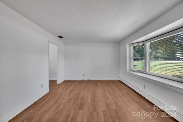 spare room featuring light wood-type flooring and a baseboard heating unit