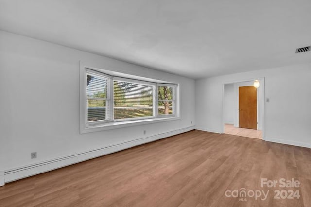 spare room with light wood-type flooring and a baseboard heating unit