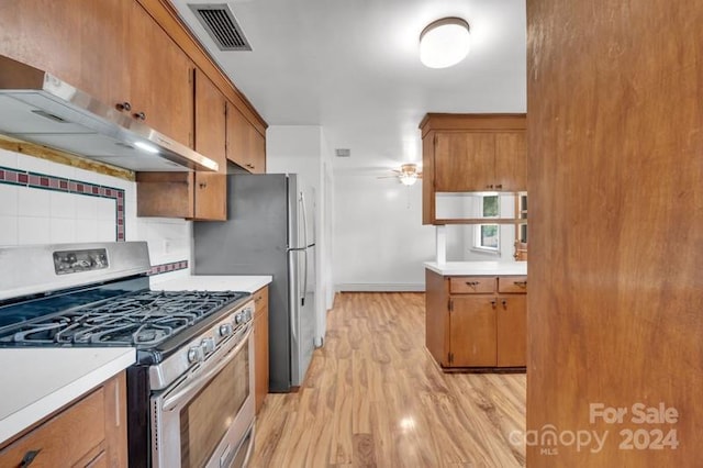 kitchen featuring gas stove, tasteful backsplash, range hood, light hardwood / wood-style flooring, and ceiling fan