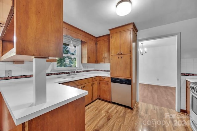 kitchen featuring sink, tasteful backsplash, appliances with stainless steel finishes, a notable chandelier, and light wood-type flooring