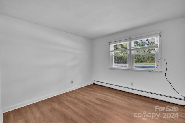 empty room with wood-type flooring and baseboard heating