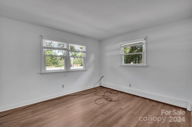 unfurnished room featuring a baseboard radiator and hardwood / wood-style floors