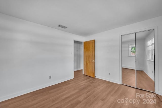 unfurnished bedroom featuring light hardwood / wood-style flooring and a closet