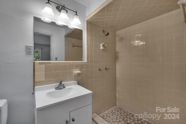 bathroom featuring a tile shower, vanity, backsplash, and toilet