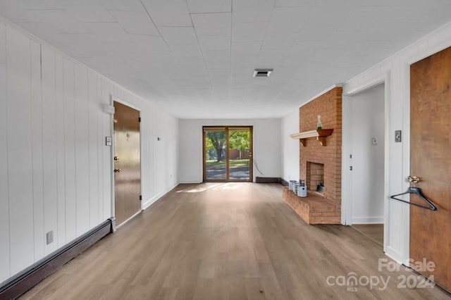 unfurnished living room with a baseboard radiator, wood-type flooring, and a fireplace