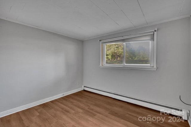 empty room with wood-type flooring, crown molding, and a baseboard radiator