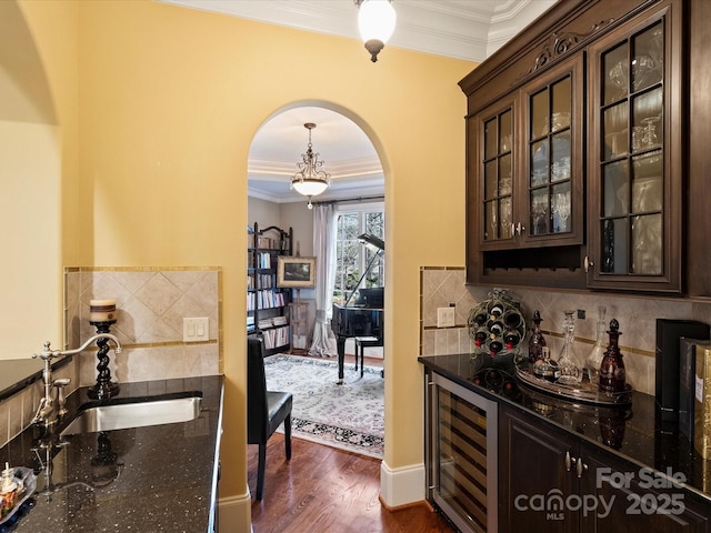 bar featuring dark wood-type flooring, wine cooler, dark brown cabinetry, and sink