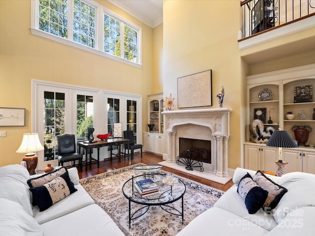 living room featuring a high ceiling, dark hardwood / wood-style flooring, crown molding, and a fireplace