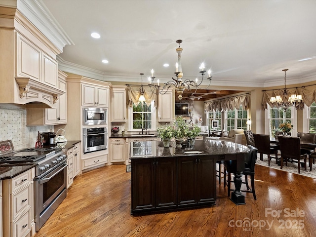 kitchen featuring appliances with stainless steel finishes, decorative light fixtures, tasteful backsplash, a notable chandelier, and cream cabinetry